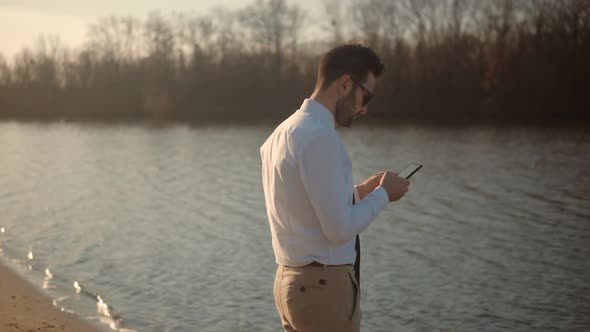 Holding Smartphone In Hands Outdoors. Using Mobile Phone On Nature. Businessman Chatting On Mobile.