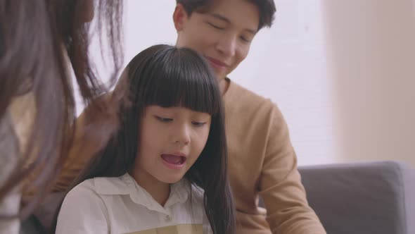 Happy parents and little daughter having fun enjoying spending leisure time together at home sitting