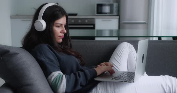 Beautiful Woman Sitting on Sofa with Laptop at Home