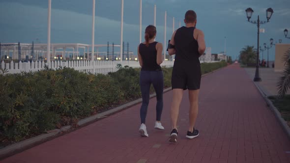 Man with His Girlfriend Are Jogging Together in Sport Area, Chatting Happily
