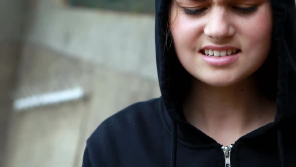 Anxious teenage girl standing in black hooded jacket