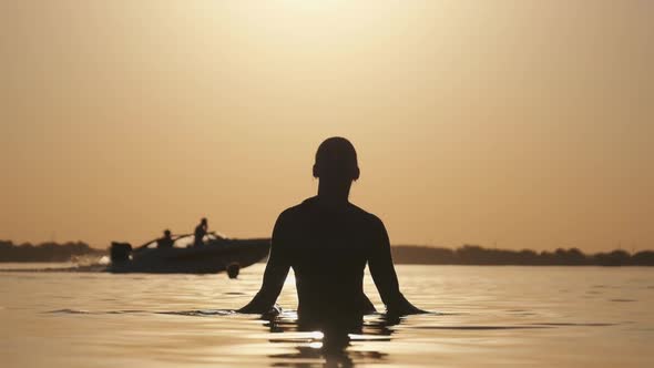 Silhouette of Young Cheerful Woman Splashing River Water at Sunset. Slow Motion