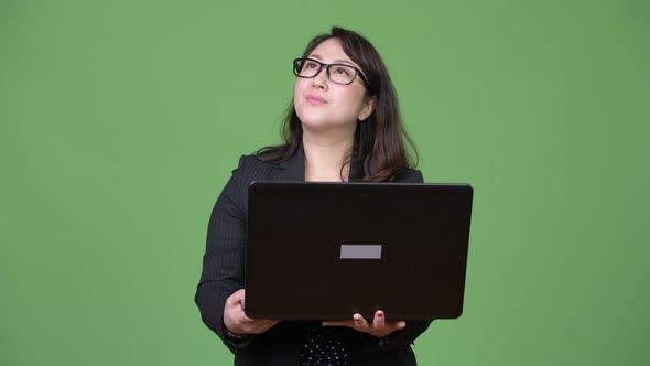 Mature Beautiful Asian Businesswoman Using Laptop Against Green Background