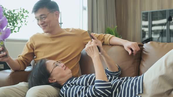 Happy senior old asian lover couple holding smartphone looking at cellphone screen