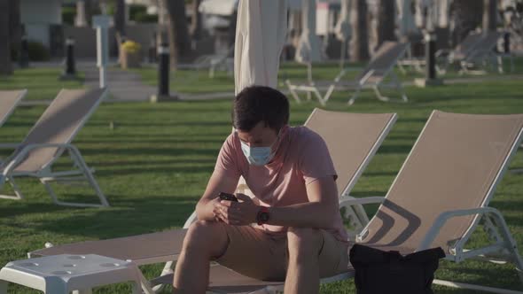 Sad Man in Protective Mask Sits on Lounger in Empty Hotel in Cyprus During Quarantine and Covid 19