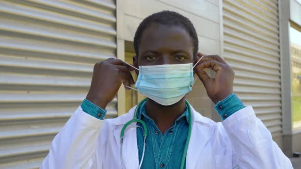 young black doctor wears the mask staring at camera - protection, virus