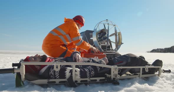 Paramedic Examining Unconscious Man Lying on Stretcher Outdoors in Winter