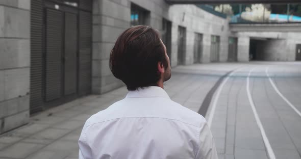 Confident Caucasian Businessman in a White Shirt Walking Along Near Office Bukding Outdoors