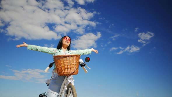 Happy Young Girl Enjoying the Sun Sitting on a White Vintage Bicycle with Basket. Hands Up To the