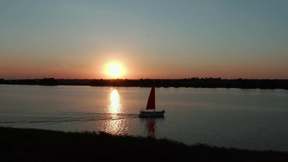 Yacht with scarlet sails at sunset, aerial view
