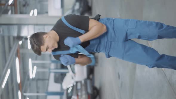 Vertical Video Joyful Young Brunette Service Man Dancing in Repair Shop Indoors