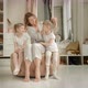 Mom and Twin Daughters in Blue Pajamas Sit in Front of the Closet at Home - VideoHive Item for Sale