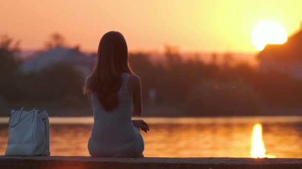 Lonely Woman Sitting on Lake Side on Warm Evening