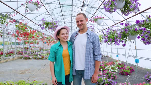 Family of Aspiring Flower Sellers Stands in Greenhouse Boy and Girl Other and Look at Camera