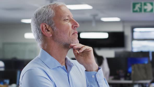 Thoughtful man rubbing his chin in office