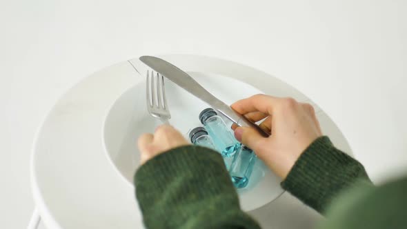 Woman is Going to Eat From White Plate with Glass Ampoules with Blue Liquid Inside Vaccination