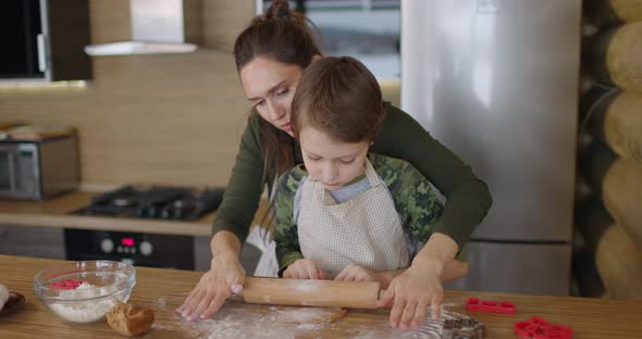 Mother and Little Son Making Handmade Cookies at Home Rolling Raw Dough Together at Kitchen