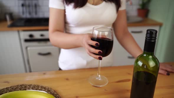 Close Up of Unrecognizable Woman Shakes Well Glass of Red Wine in Kitchen