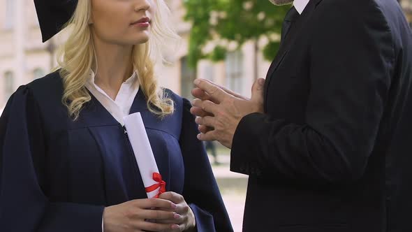 Teacher gives life instructions to female graduate student in academic dress