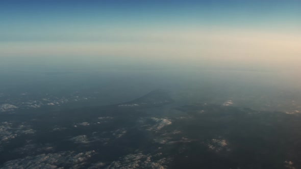 Airplane Flying Over Land And Coastline With Sunlight