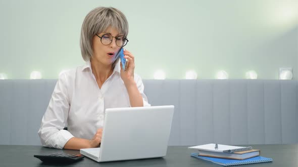 An Elderly Businesswoman Indignantly Communicates with Her Employees on the Phone and Solves