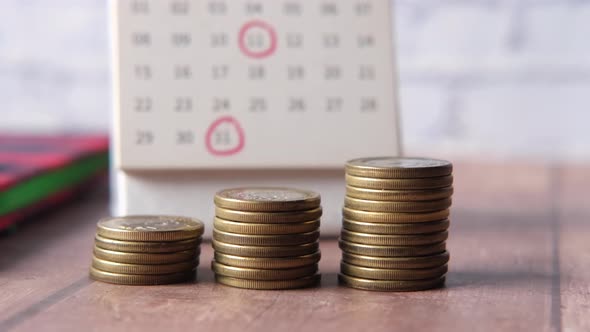 Stack of Coins and Calendar on White Background