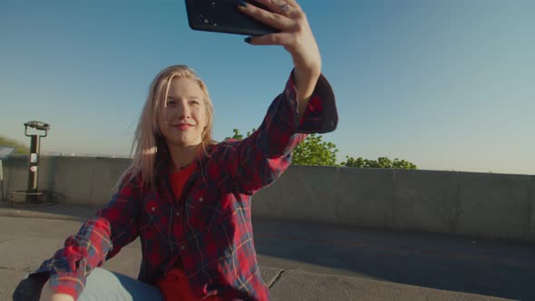 Cool Female Skateboarder on Skateboard Making Selfie at Daybreak