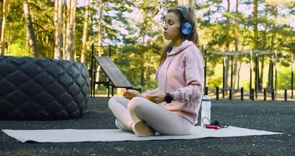 A Young Woman Chooses Music for Meditation on Her Smart Watch and Starts Meditating