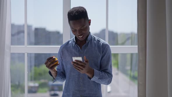 Excited African American Businessman Making Victory Gesture Checking Ebusiness on Smartphone