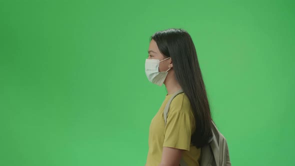 Side View Of Asian Girl Student Wearing Mask And Walking To School On Green Screen Chroma Key