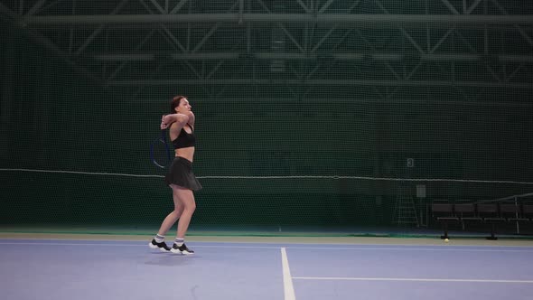 Tennis Training or Game on Indoor Court Young Woman is Striking Ball By Tennis Racquet Fulllength