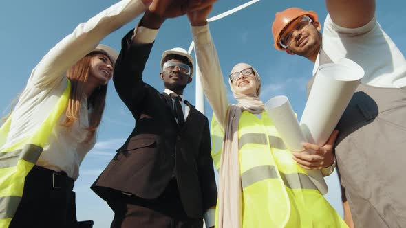 Group of Four Multicultural Partners Stacking Hands Together and Smiling on