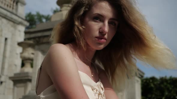 Beautiful Girl with Curvy Hair Against the Background of the Old Building