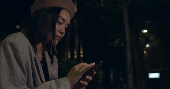 Side View of Attractive Millennial Woman in Beret Hat Scrolling, Touching and Zooming Phone Screen