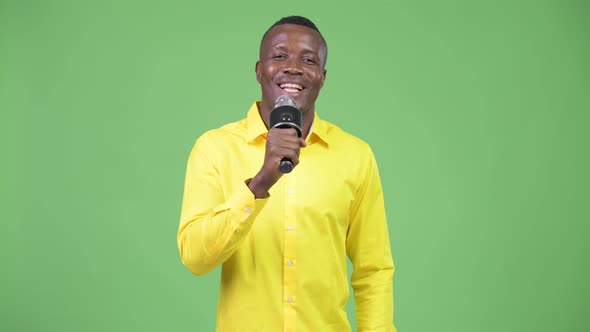 Young Happy African Businessman Singing with Microphone