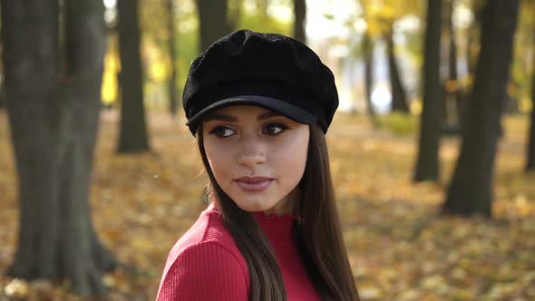 Girl in a Beret Rejoices Poses and Looks Flirty at Camera in Sunny Autumn Park