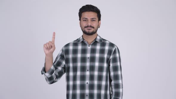 Portrait of Young Happy Bearded Indian Man Pointing Up