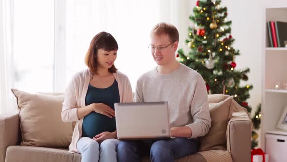 Man and Pregnant Wife with Laptop on Christmas