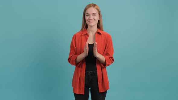 Pretty Girl with Blond Hair Applauds While Sitting on the Turquoise Background.