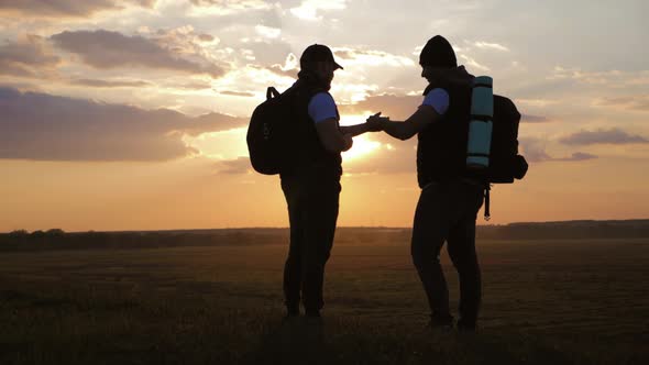 The Silhouette of Two Man Standing on the Top of Mountain with Backpacks and Use Phone