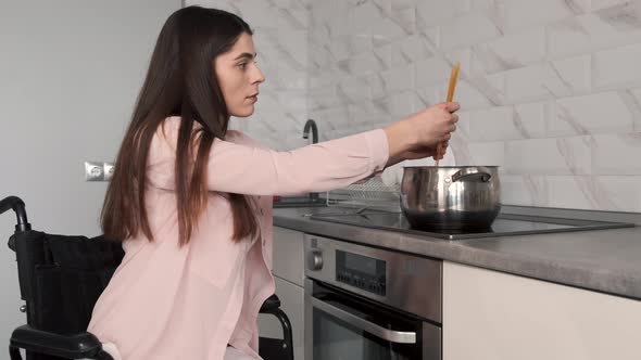 Young Handicapped Woman On Wheelchair Cleaning Stove