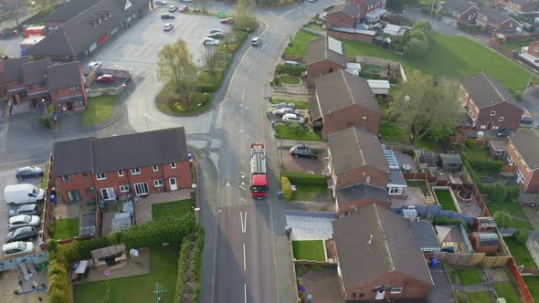 A bin lorry, refuse collection vehicle makes it way up the road as men load recycling bins into the