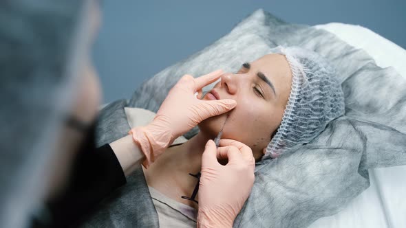 The Beautician Makes an Injection Into the Woman's Face