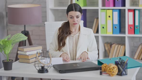 Portrait of Stressed Annoyed Young Woman Calming Down Sitting in Office Using Breathing Exercises