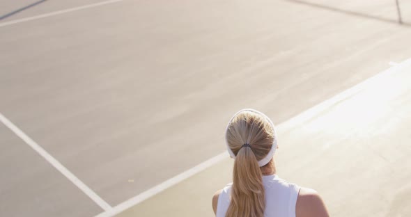 Video of back of caucasian female tennis player holding racket and hitting ball