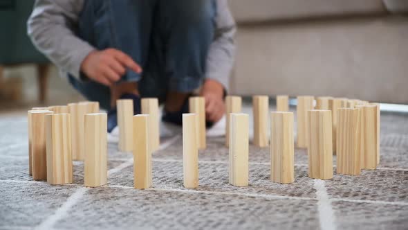 Child Pushing Wooden Block and Starting Domino Effect