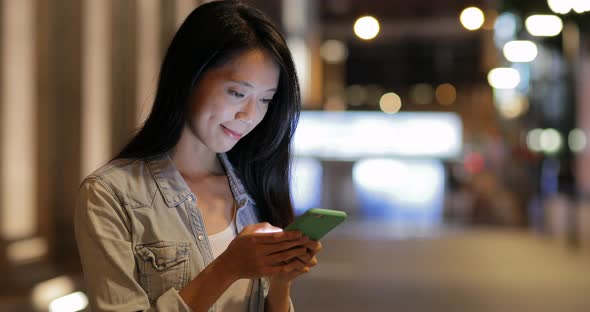 Woman using cellphone at night in Hong Kong 