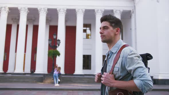 Attractive Young Handsome Man Tourist with Backpack Walking in City Center and Looking Around Slow