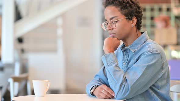 Worried African Woman Sitting in Cafe and Thinking 