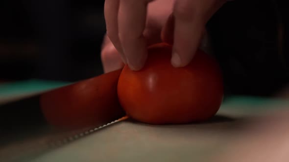 Back View of Cutting Large Tomato on Thin Slices